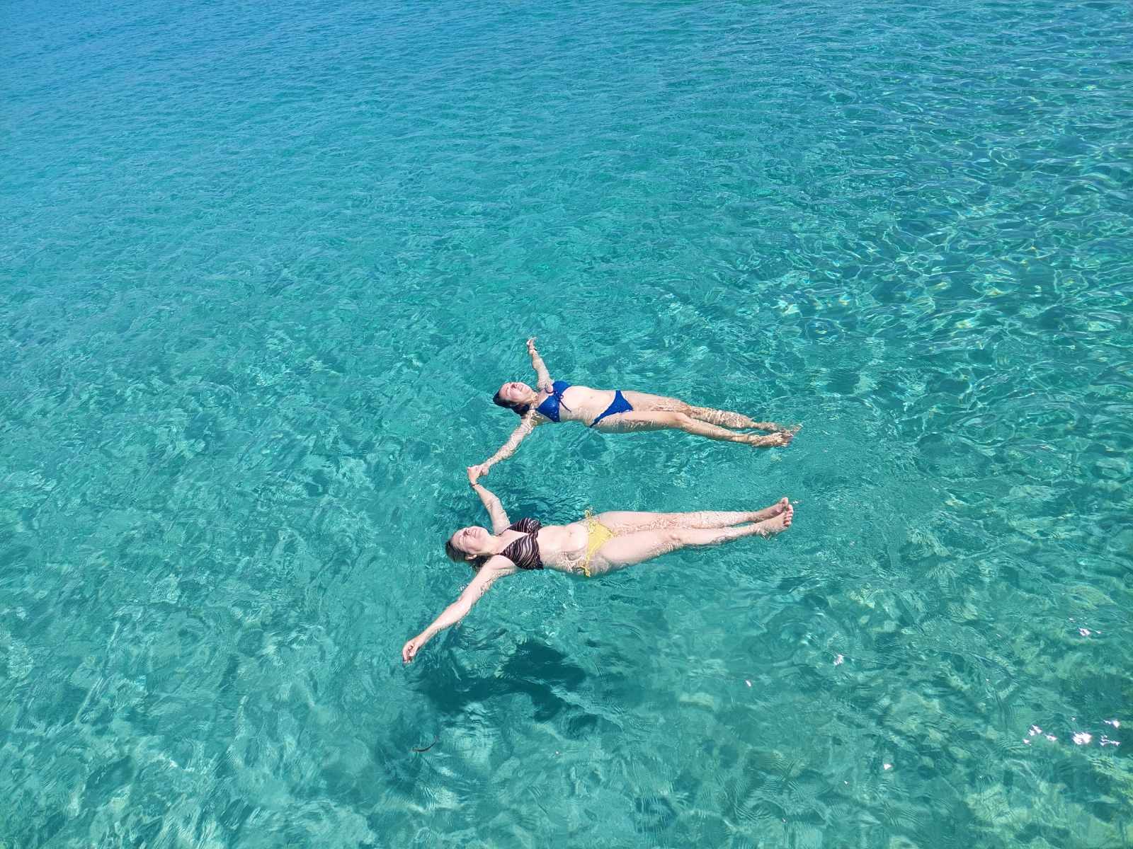 Two guests floating in the clear turquoise water off Paros